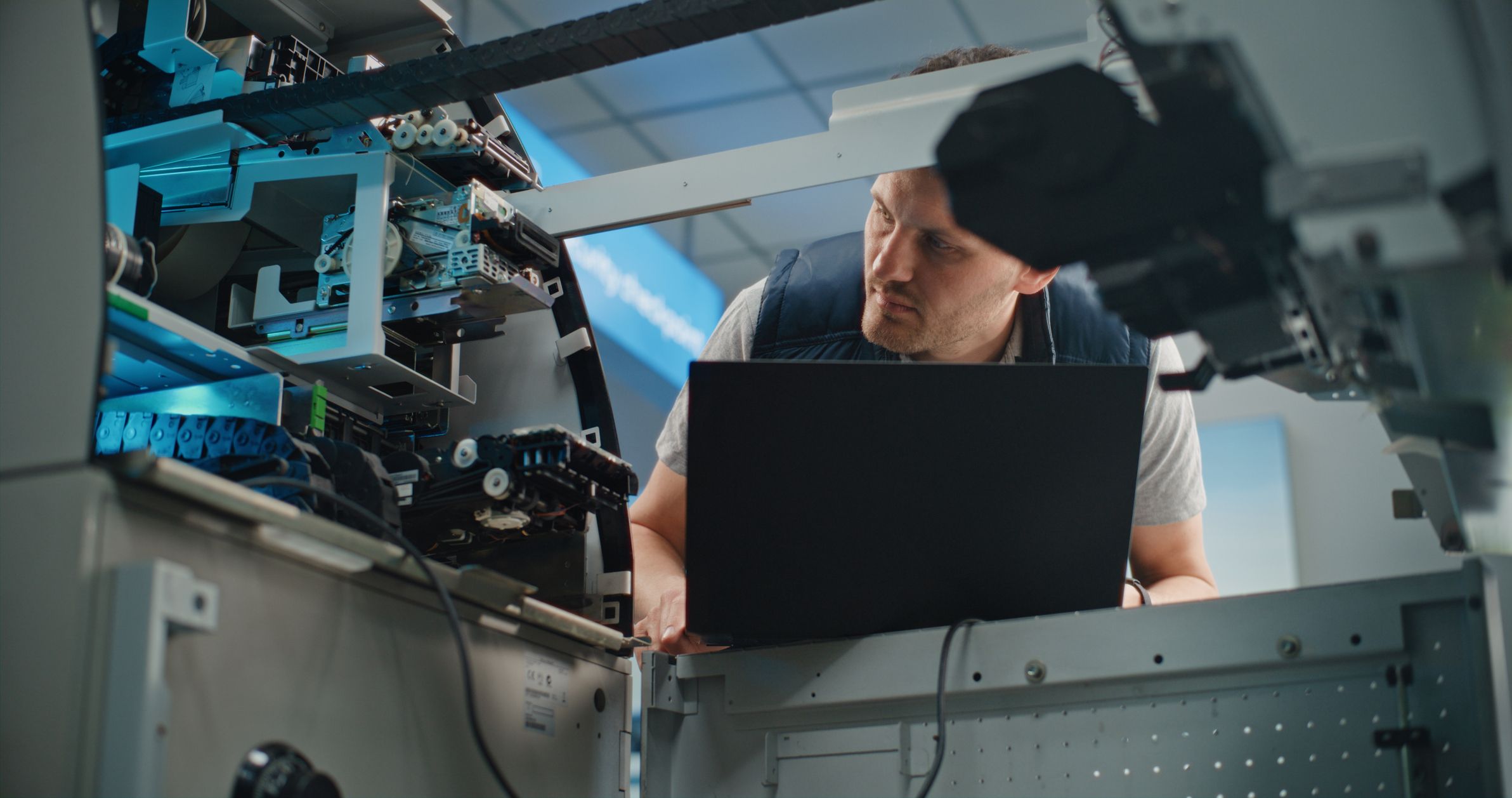 Man with laptop working on ATM
